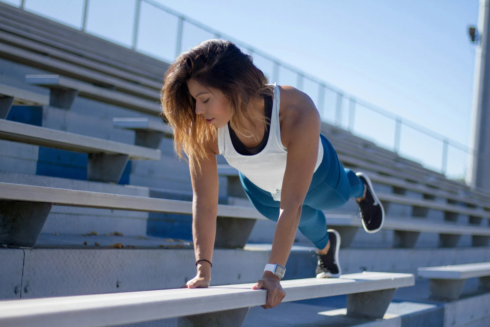Woman doing incline push ups on stadium benches