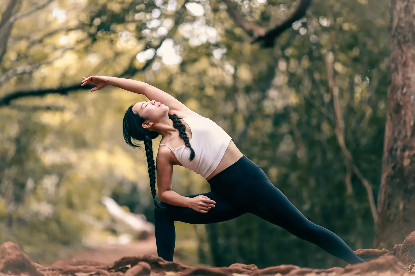 Woman holding a side angle stretch in a forest